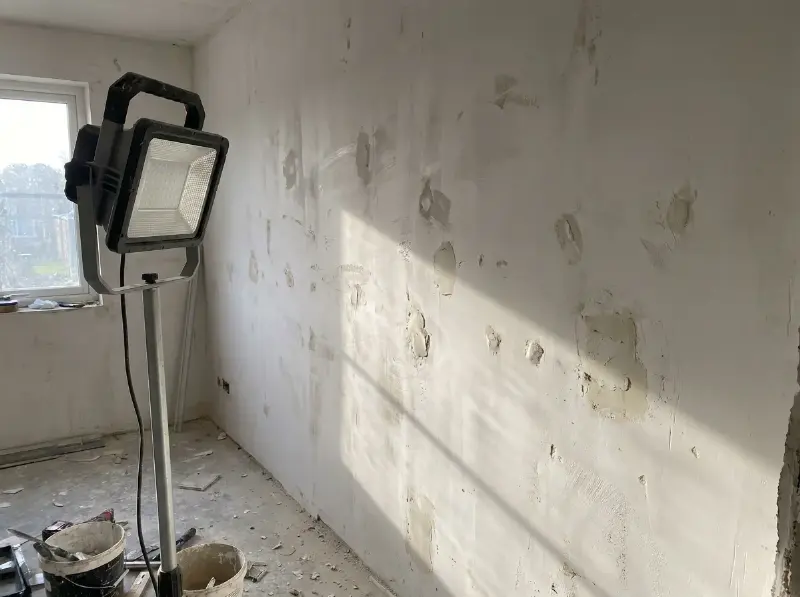 Werklamp die een geplamuurde muur in strijklicht zet om oneffenheden te tonen voor het schilderen